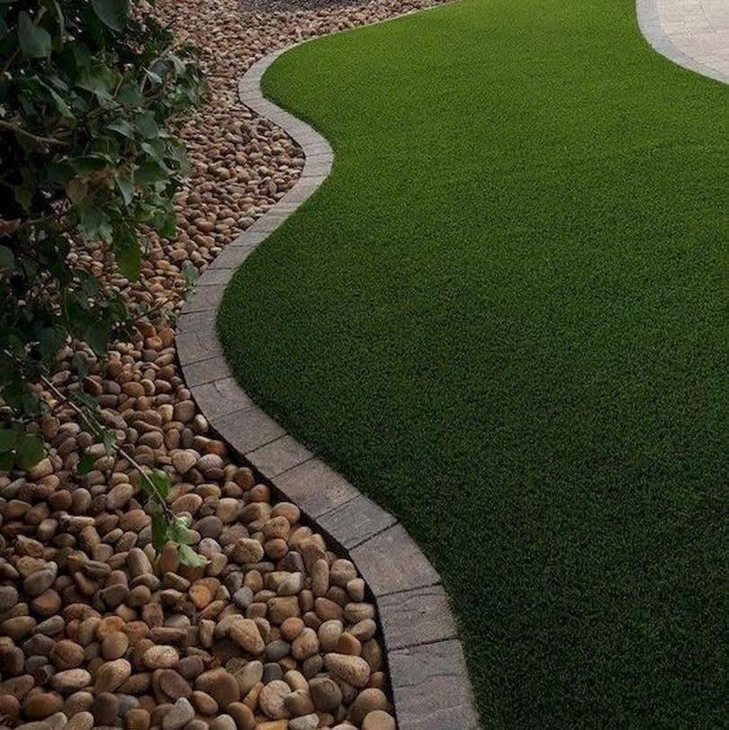 Curved artificial turf edge bordered with river rock